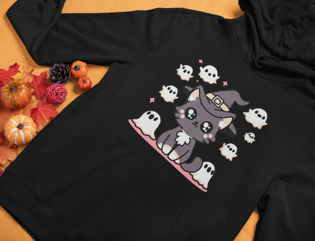 Black hoodie with a Halloween-themed design of a cat in a witch hat surrounded by ghosts on a wooden surface.
